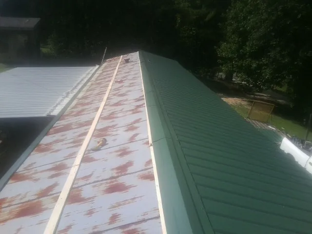 Old rusted panels beside newly installed green metal roofing — Wind Damage Roof Repair by Roofing Brothers in North Richland Hills