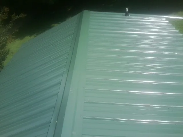 New green metal panels meeting at the ridge of a roof — Flat Roof Repair work by our crew in North Richland Hills