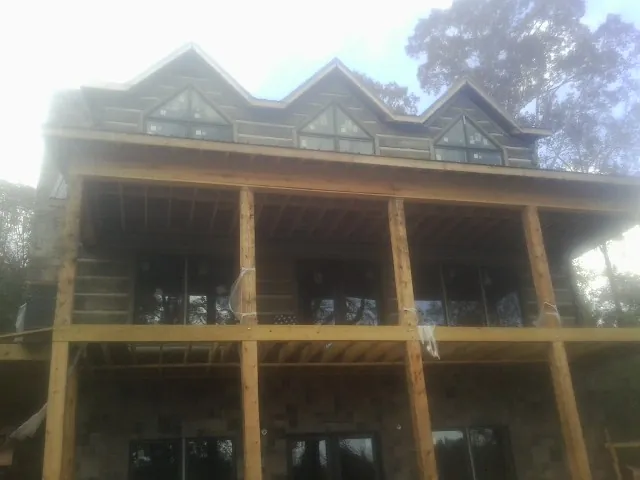 Dormers and porch framing on a large log home under construction — Roof Coating work by our crew in North Richland Hills