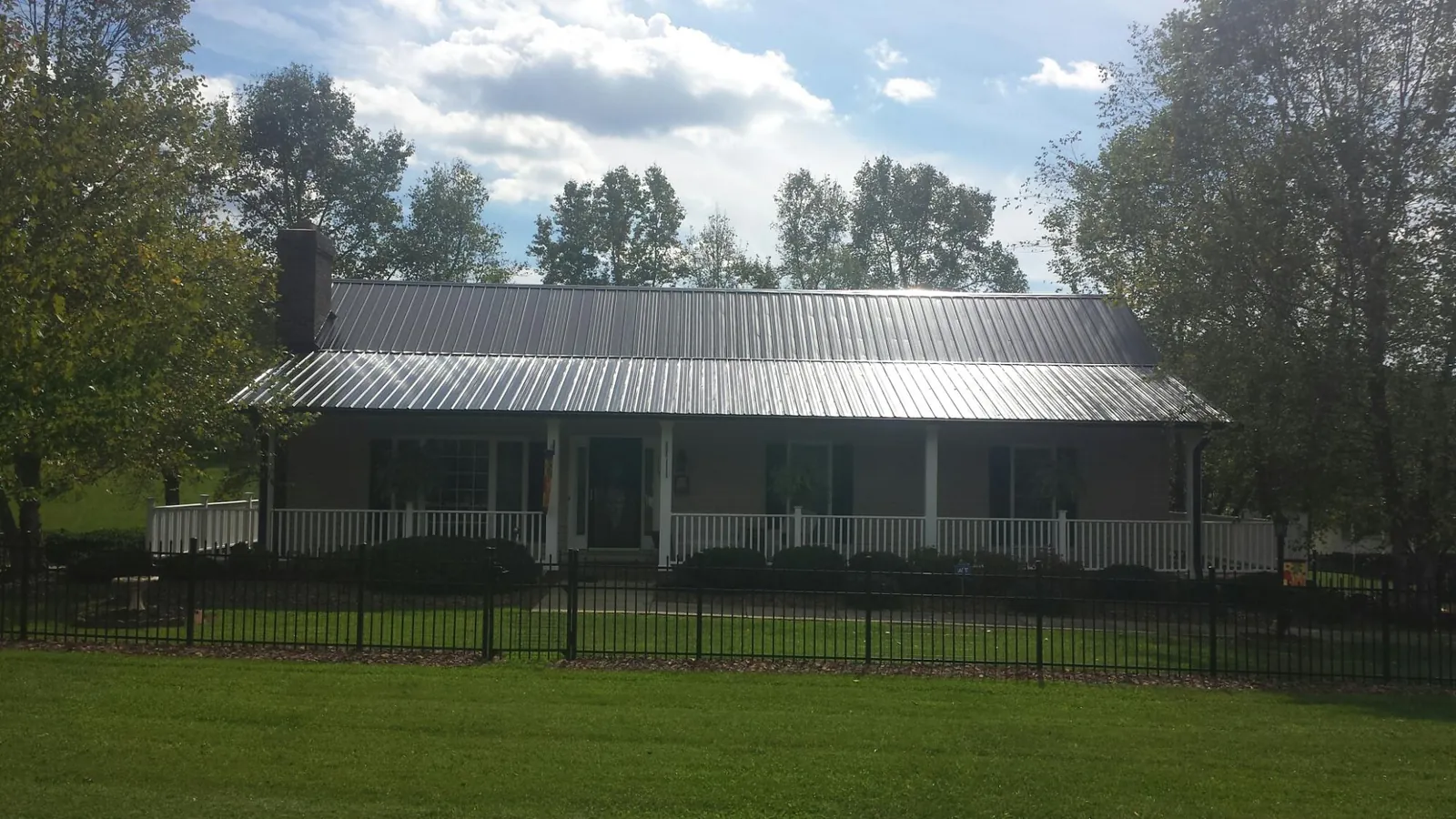 Gray metal roof on a brick ranch with a full width front porch — Gutter Guard Installation work by our crew in North Richland Hills