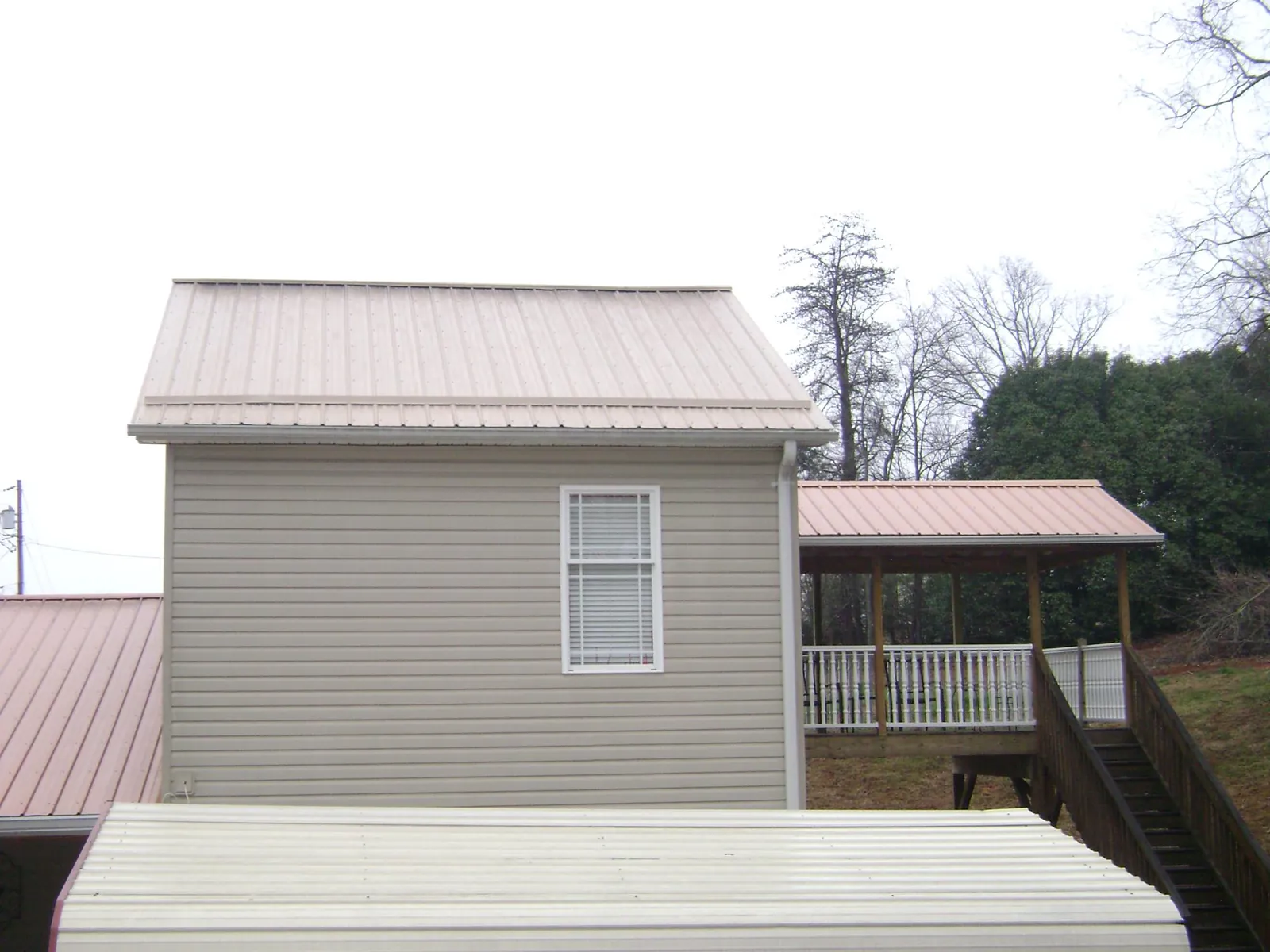 Tan metal roofs on a two story addition and attached porch, from a Roof Replacement job in North Richland Hills