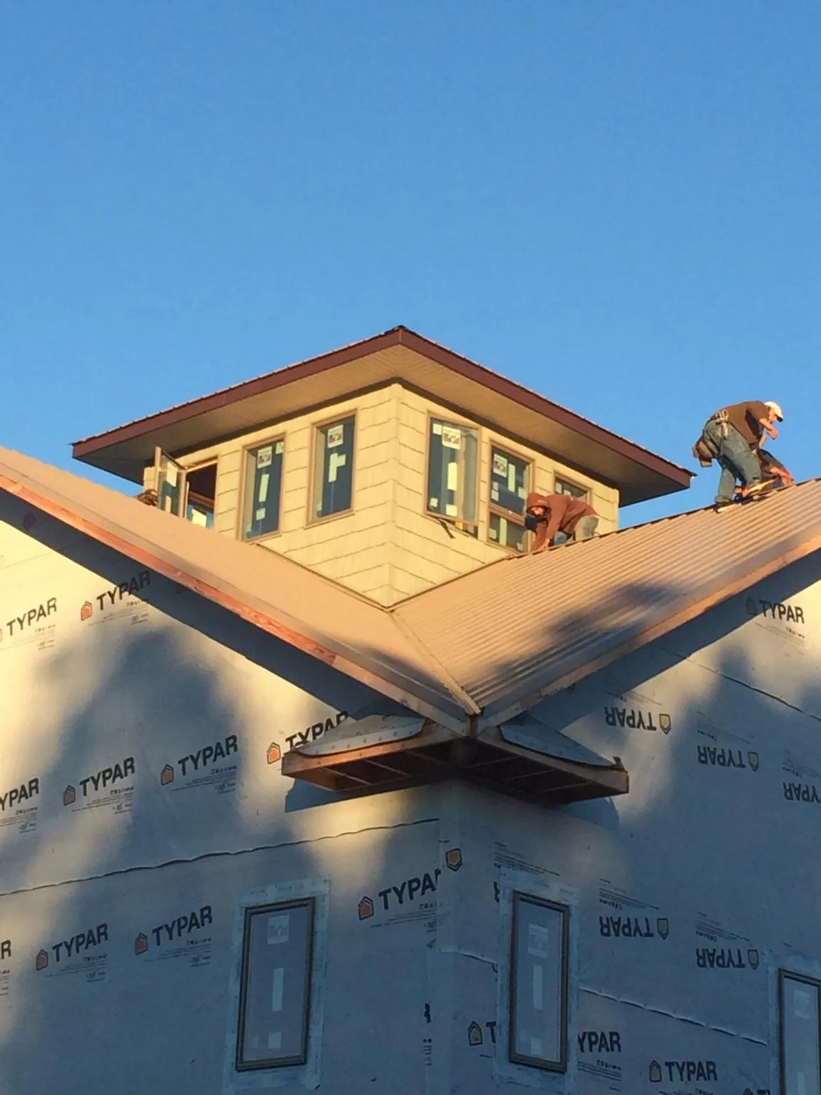 Roofers working around a rooftop cupola on a new metal roof at sunset — Roof Waterproofing in North Richland Hills by Roofing Brothers